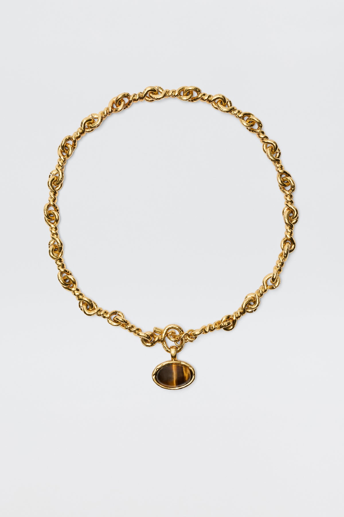 The Zandra - Gold features a chunky, vintage-inspired gold-plated chain with twisted links and an oval dark brown gemstone pendant set in a gold frame, shown against a plain white background.