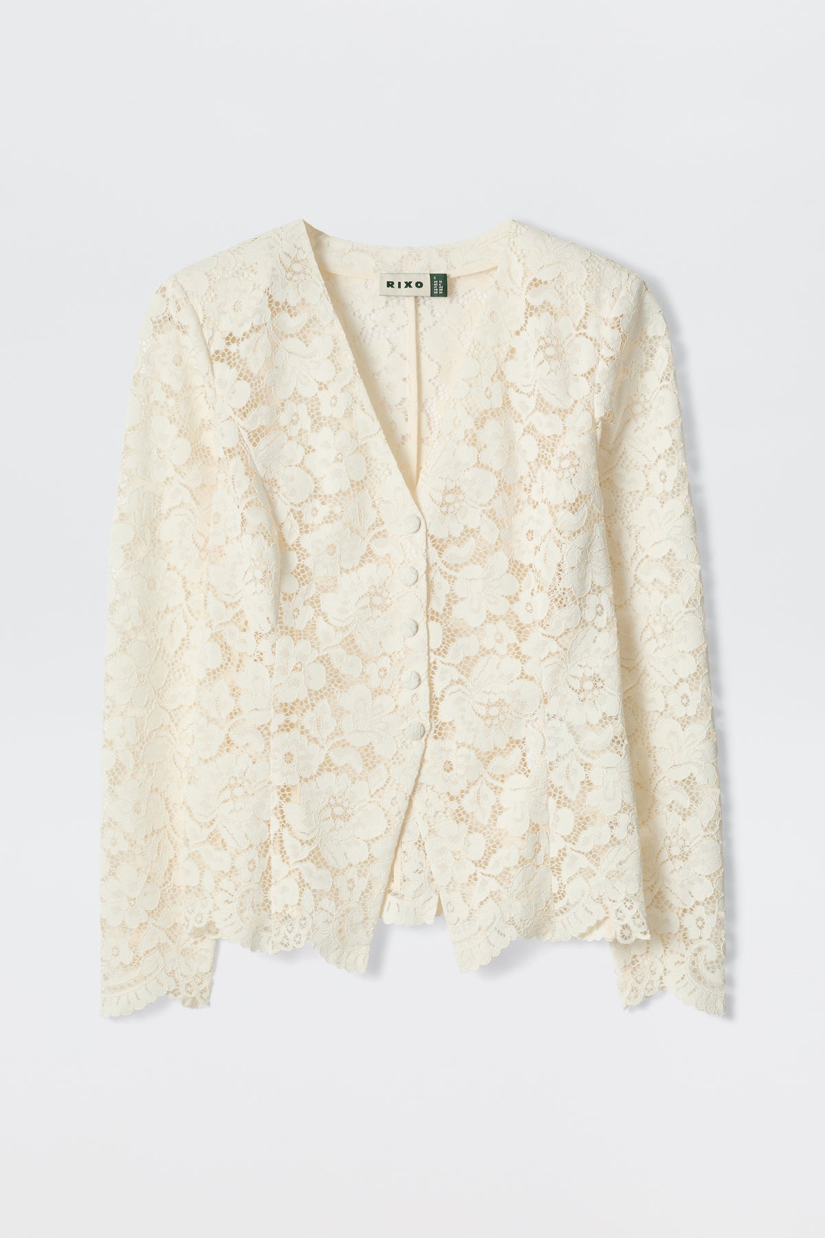 The Padma - Cream is an off-white, long-sleeved lace cardigan with a V-neckline and delicate floral pattern, shown flat on a light background.