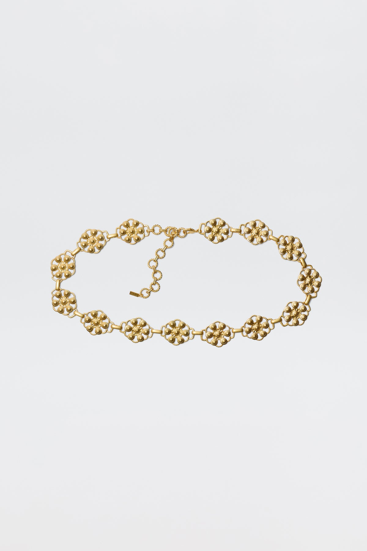 The Tiana - Gold necklace showcases vintage-gold plating with linked, textured floral motifs and an adjustable chain clasp, styled like a daisy-chain belt and displayed against a plain white background.