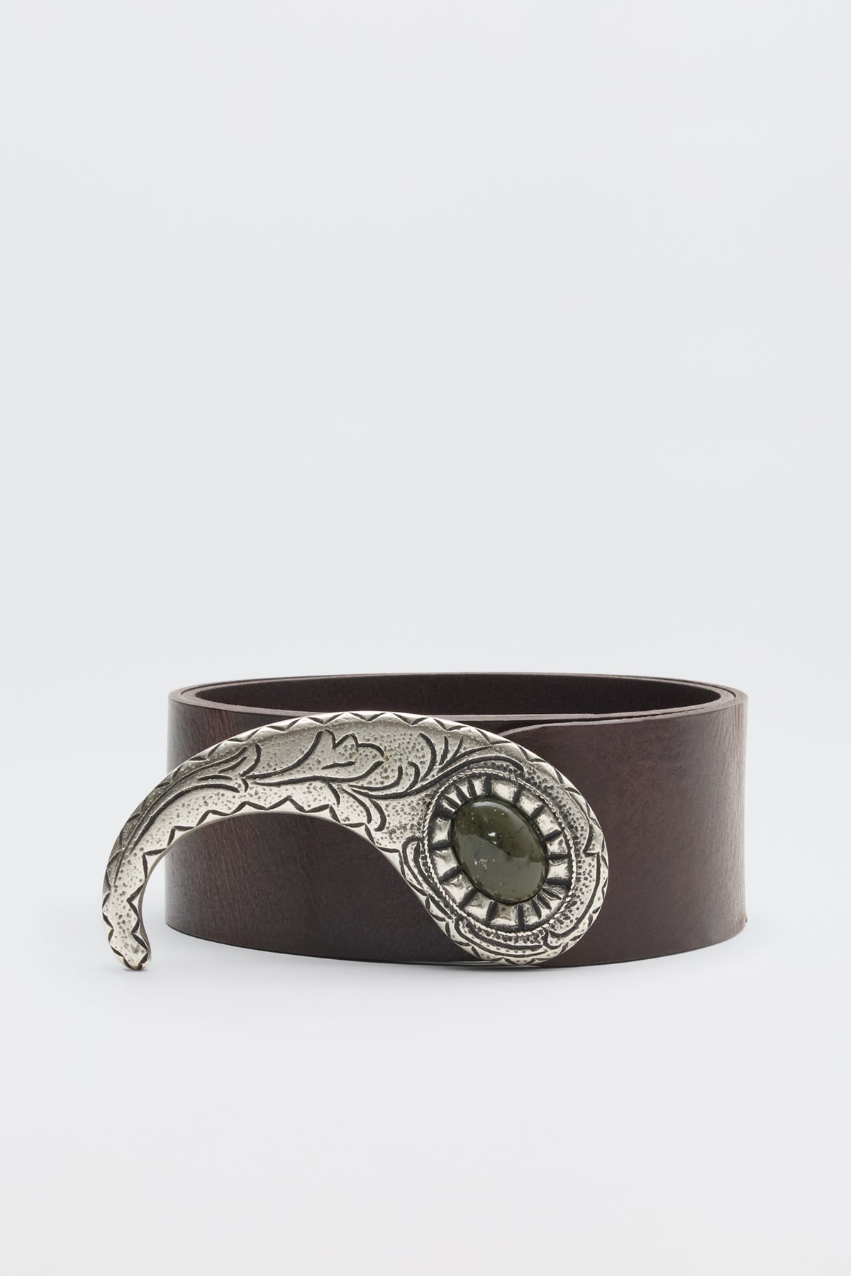 The Daniella - Dark Brown is a leather belt with a large, ornate silver buckle featuring engraved details and a central dark green stone, shown against a plain white background.