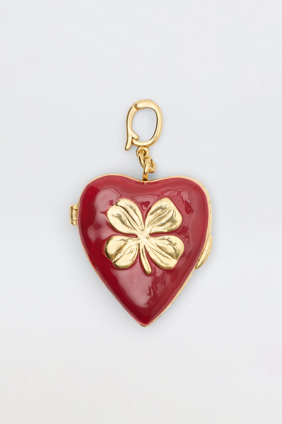 The Ardina - Red is a heart-shaped red locket featuring a gold four-leaf clover on the front and a gold clasp, displayed on a plain white background.