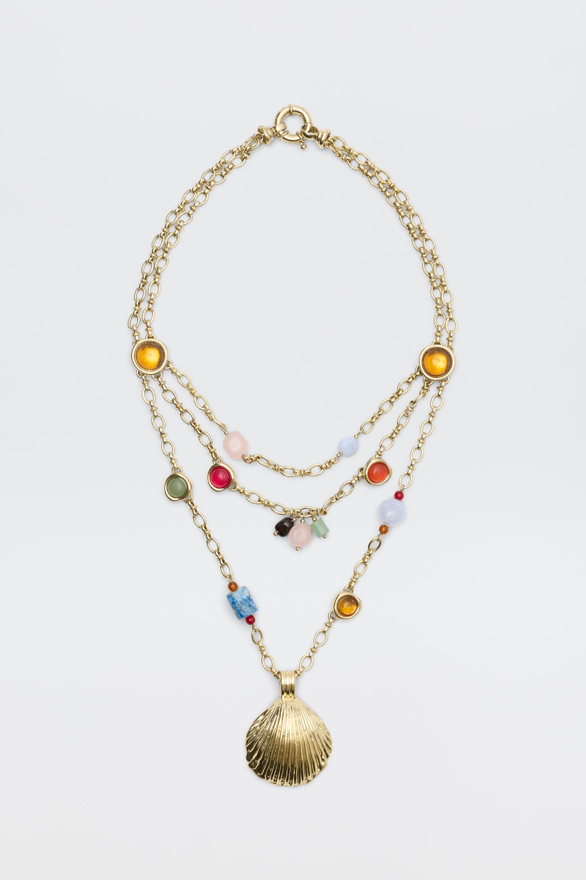 Lima - Gold necklace featuring three layered gold chains adorned with colorful beads, round yellow and green accents, and finished with a large gold seashell pendant, displayed on a plain white background.