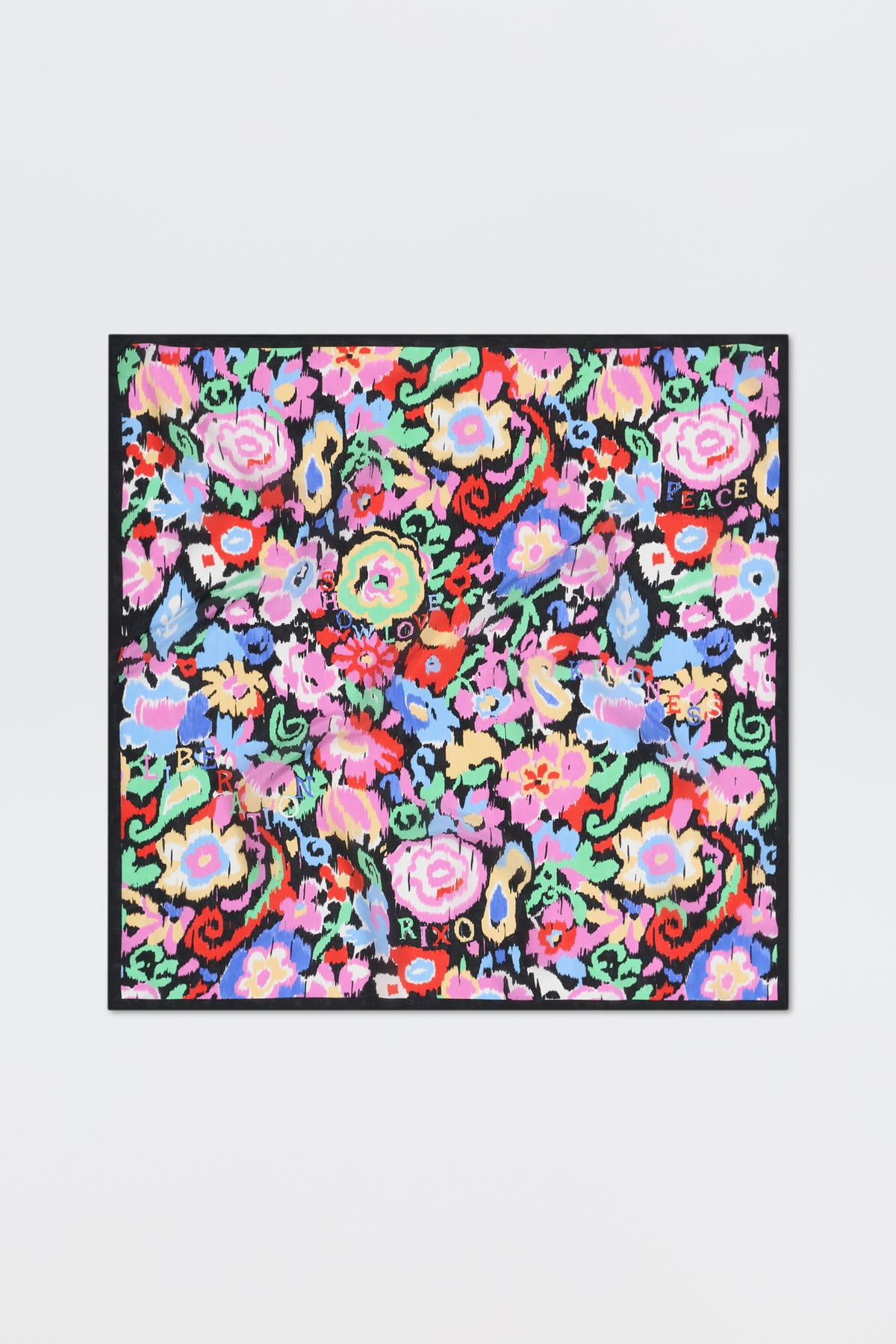 Introducing “Menno - Ikat Bloom”: a colorful square scarf featuring a vibrant floral pattern with words like LOVE, PEACE, and XOXO scattered among red, pink, blue, and green flowers on a black background.
