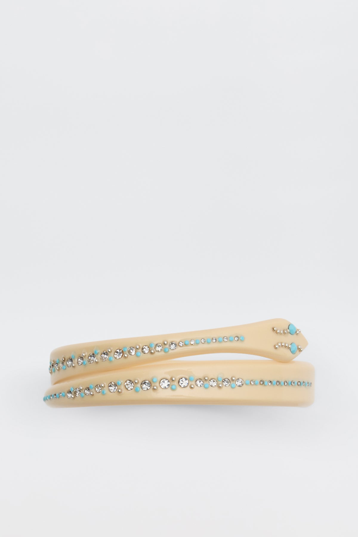 The Shereen - Cream headband features rows of small, round turquoise and clear rhinestones on a beige band, shown against a plain white background.
