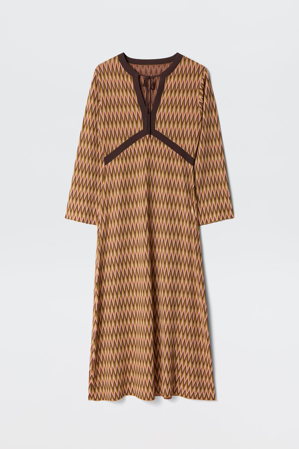 The Pamela - Maeve Jacquard Multi is a long-sleeved, knee-length dress featuring a brown, yellow, and beige zigzag pattern with dark brown trim along the neckline and chest, shown on a plain white background.