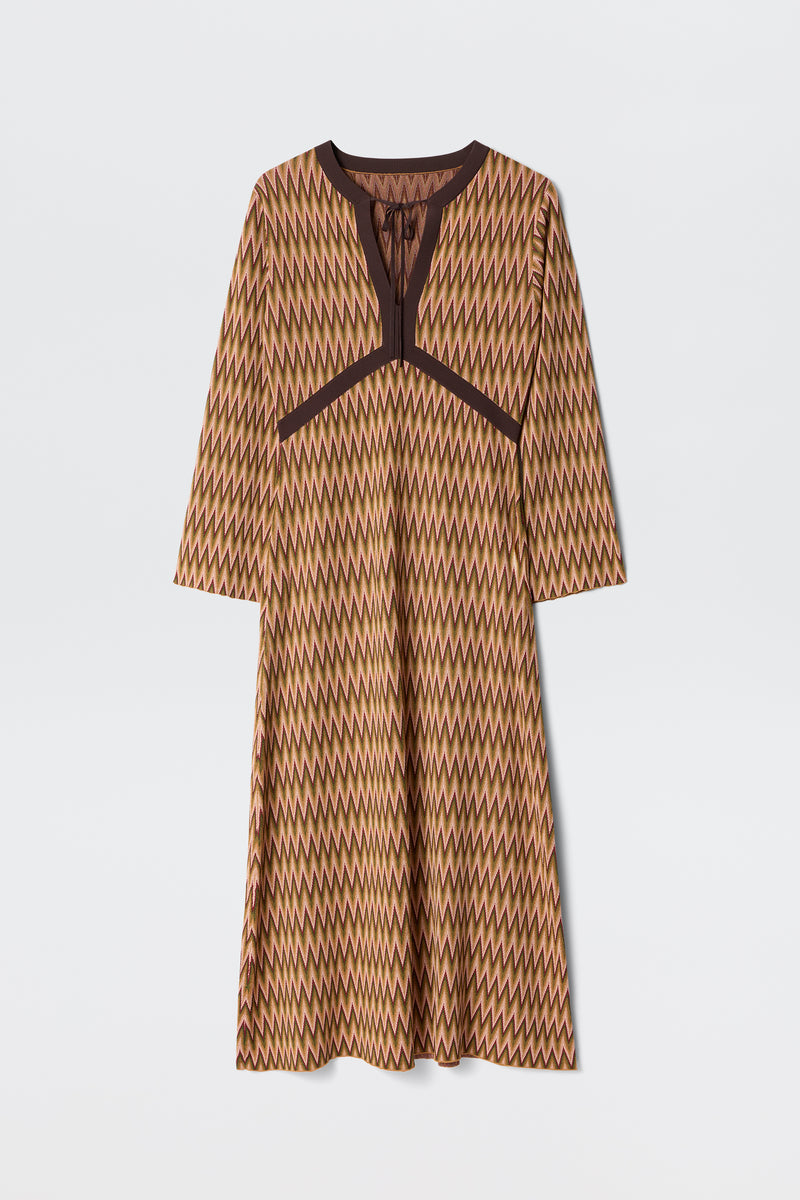 The Pamela - Maeve Jacquard Multi is a long-sleeved, knee-length dress featuring a brown, yellow, and beige zigzag pattern with dark brown trim along the neckline and chest, shown on a plain white background.