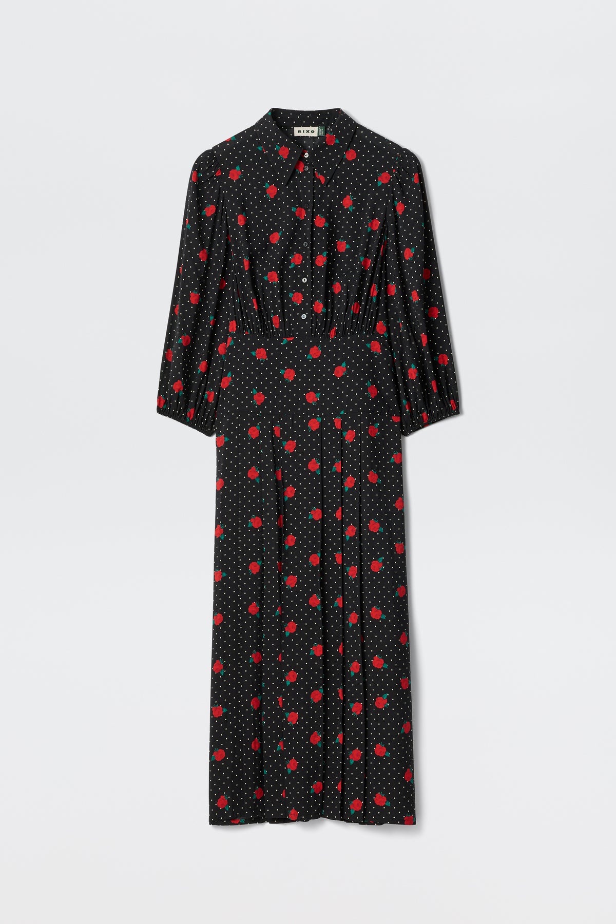 The Izzy - Rose Spot Black is a long black dress with white polka dots and red floral patterns, featuring long sleeves, a collared neckline, and a slightly fitted waist.
