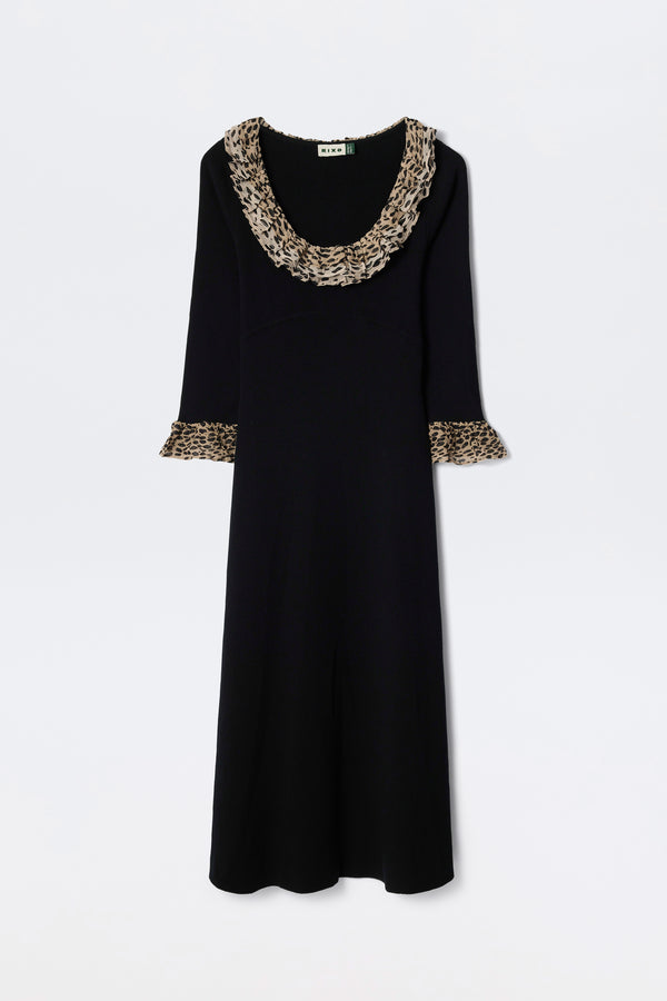 The Mika - Antelope Spot Black is a long-sleeved black scoop neck dress with wide ruffled neckline and sleeve cuffs, featuring a brown and black antelope spot print, displayed on a plain white background.