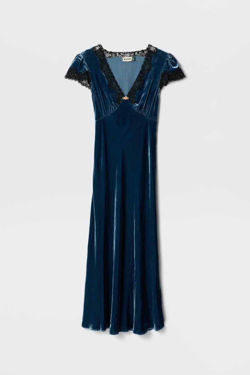 The Clarice - Steel Blue dress features blue velvet fabric, short sleeves, a V-neckline with black lace trim, and a fitted waist. Displayed against a plain white background.