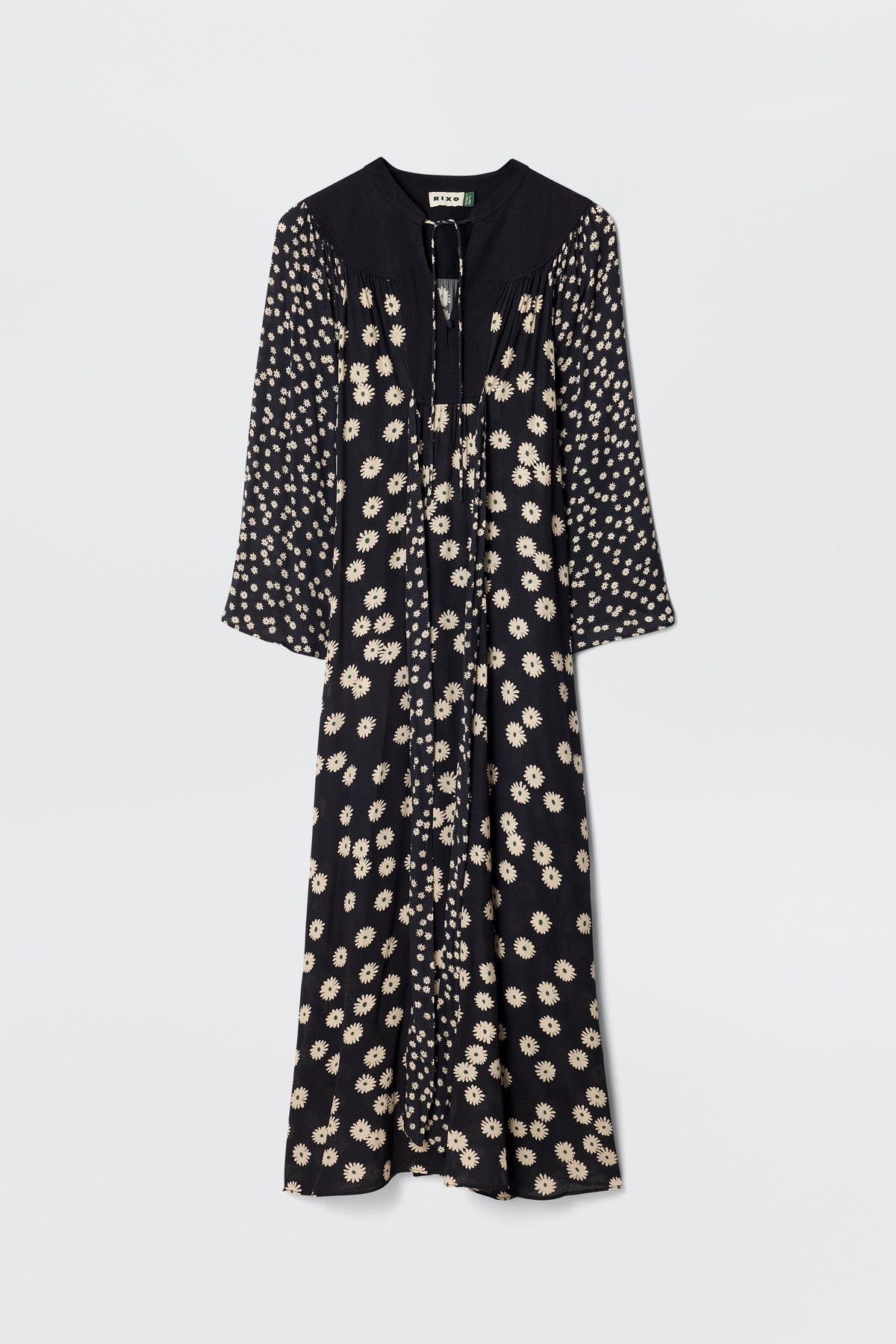 The Anela - Daisy Mix Black is a long-sleeved, lightweight black crepe boho dress with a cream floral print, V-neckline with ties, and a loose, flowy silhouette—perfect for everyday wear against a plain white background.