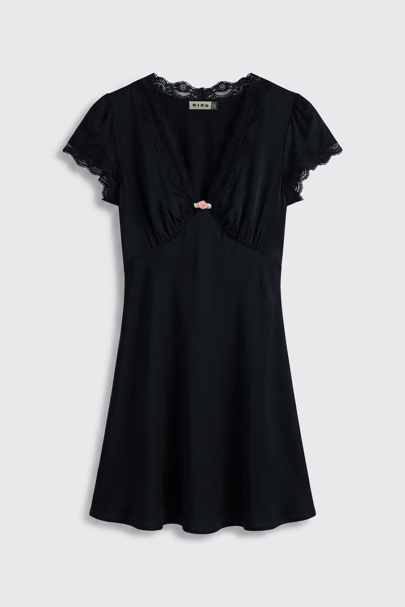 Cely - Black: A short-sleeved black dress featuring lace trim at the neckline and sleeves, a V-shaped front, and a small pink bow accent centered on the chest, showcased against a plain light background.