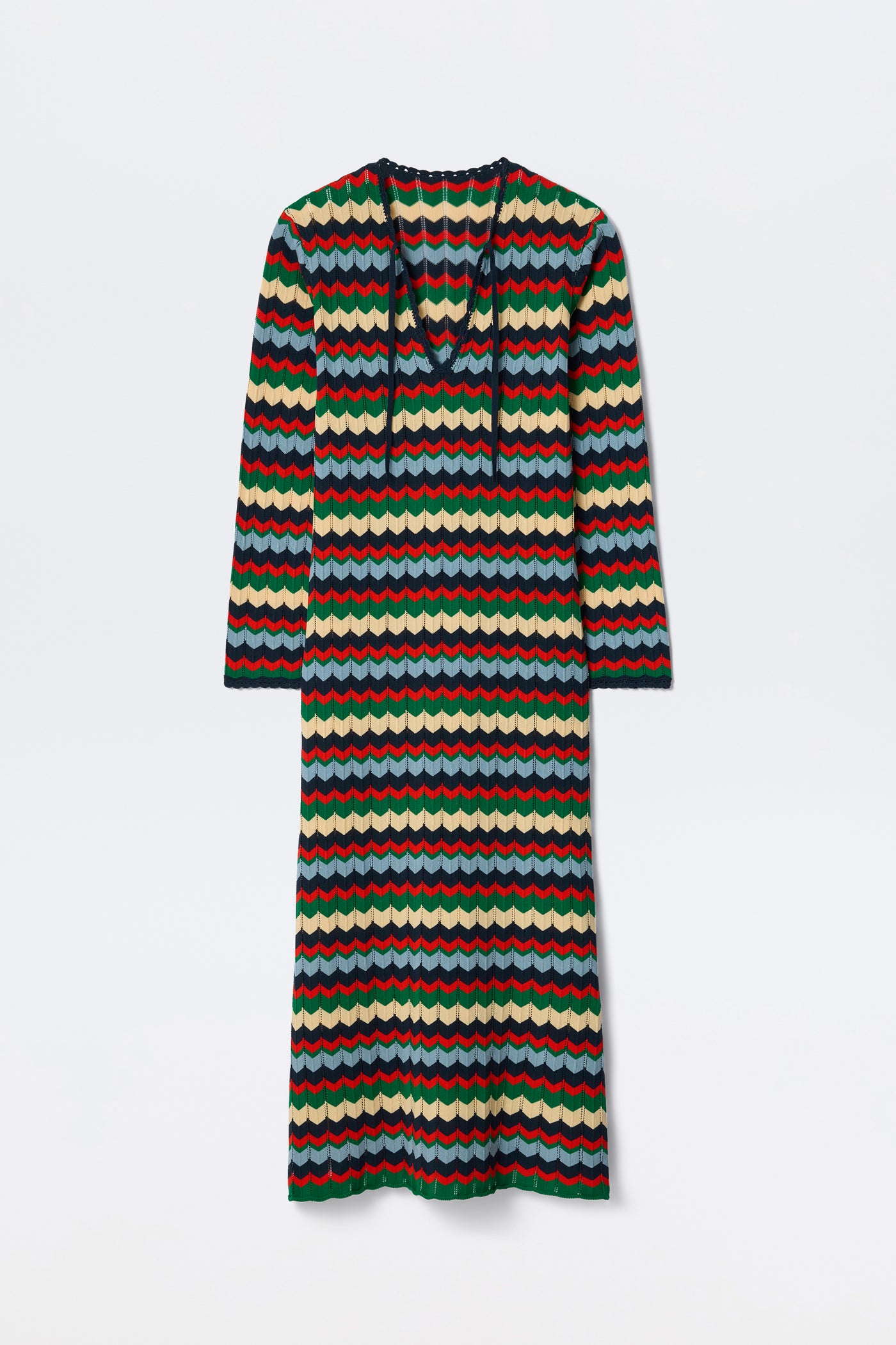 The Lucila - Retro Chevron Blue is a long-sleeved, ankle-length dress featuring a colorful wavy striped pattern in red, green, blue, and cream. It has a V-neck with a tie detail and offers a relaxed fit.