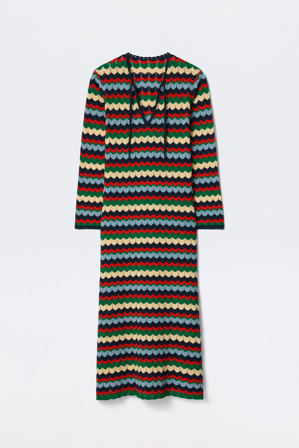 The Lucila - Retro Chevron Blue is a long-sleeved, ankle-length dress featuring a colorful wavy striped pattern in red, green, blue, and cream. It has a V-neck with a tie detail and offers a relaxed fit.