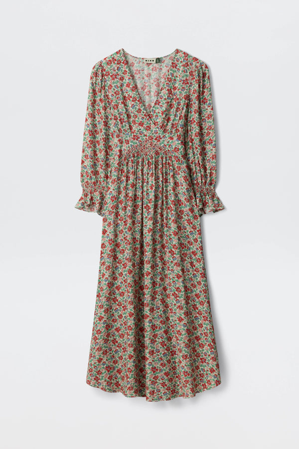 The Mireta - Jeannie Bloom Ivory is a long-sleeved, ankle-length dress with a red and green floral pattern, V-neckline, gathered waist, and slightly flared cuffs, displayed against a plain white background.