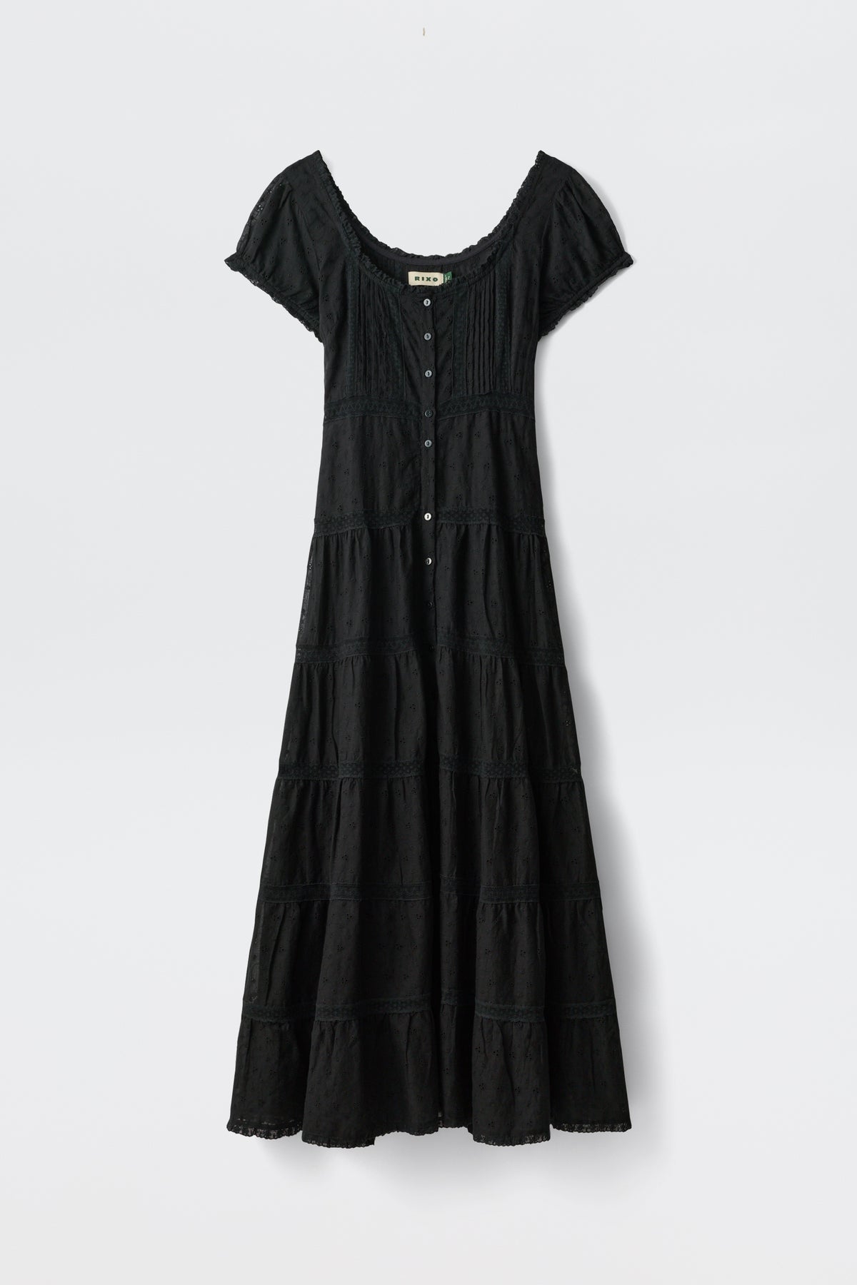 The Jaclyn - Black is an ankle-length, short-sleeve dress with a scoop neckline, button-down front, fitted bodice, flared tiered skirt, and subtle texture details. Shown against a plain white background.