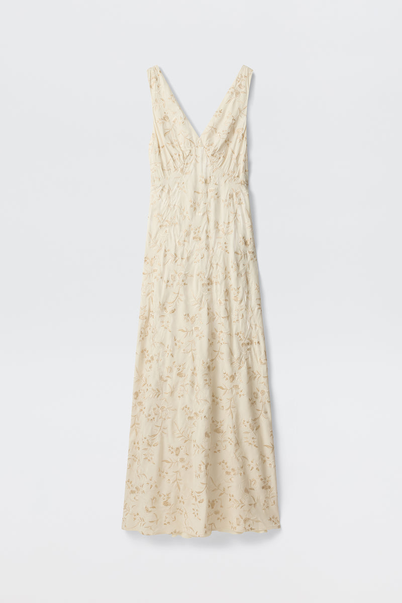 The Fawn - Botanical Embroidery Pearl is a sleeveless, cream maxi dress with a V-neckline, delicate light floral embroidery, and a form-fitted silhouette, displayed against a plain white background.