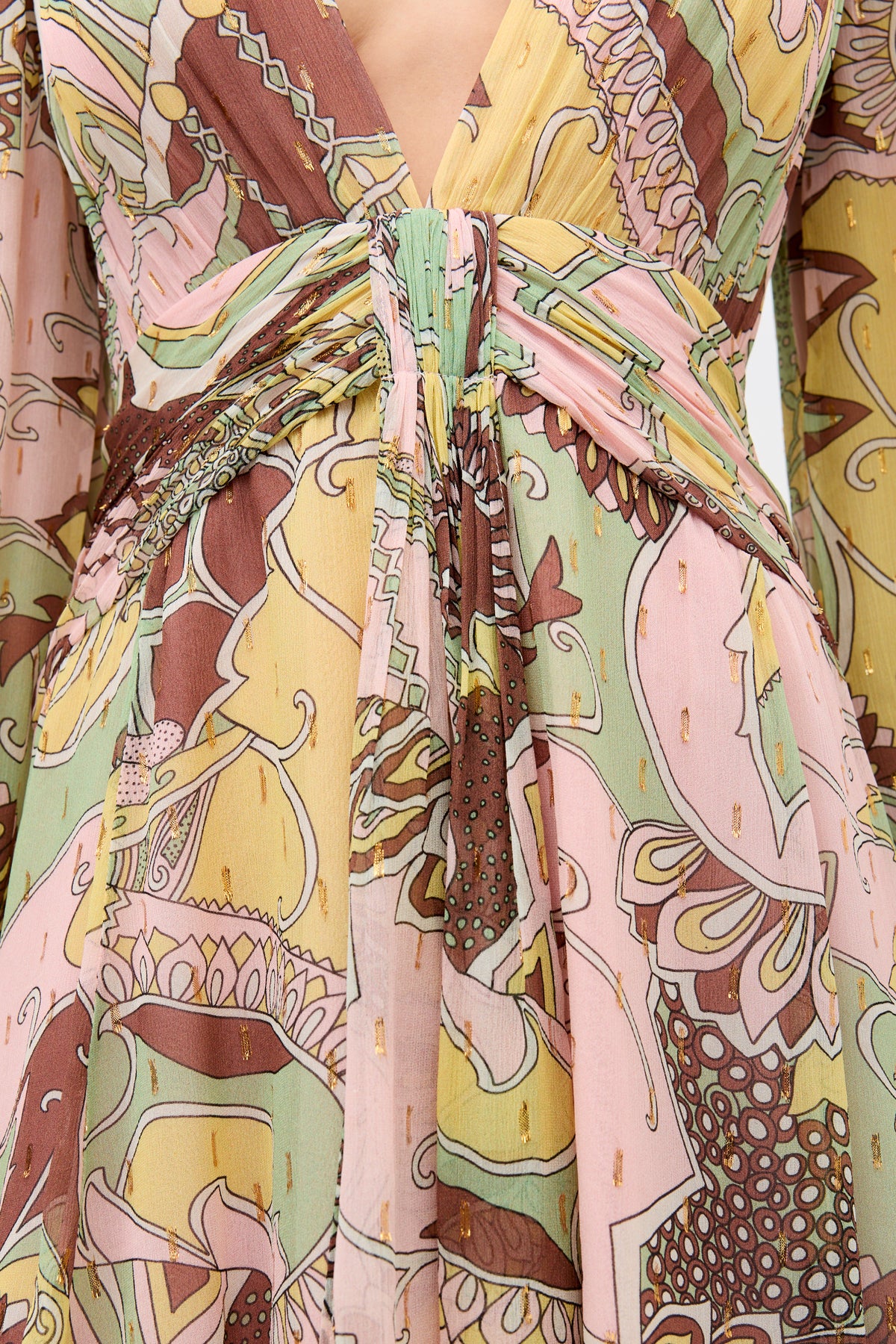 A close-up of a person wearing the Clove - Bianca Abstract Green dress, featuring vibrant pink, yellow, green, and brown patterns with a deep V-neckline and a knotted waist detail.
