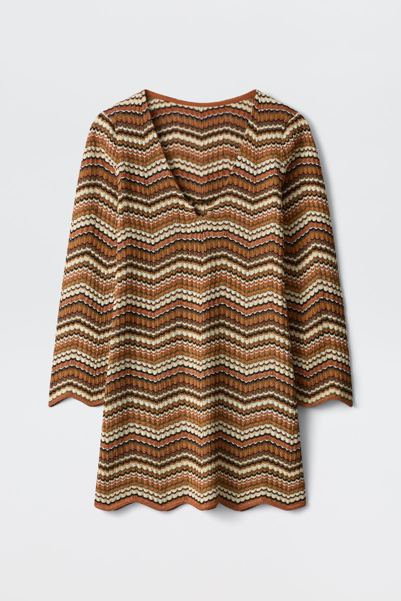 The Ivia - Maria Chevron Brown top is a long-sleeve V-neck with wavy brown, cream, and black stripes. It features scalloped hems on the sleeves and edge, shown laid flat against a white background.