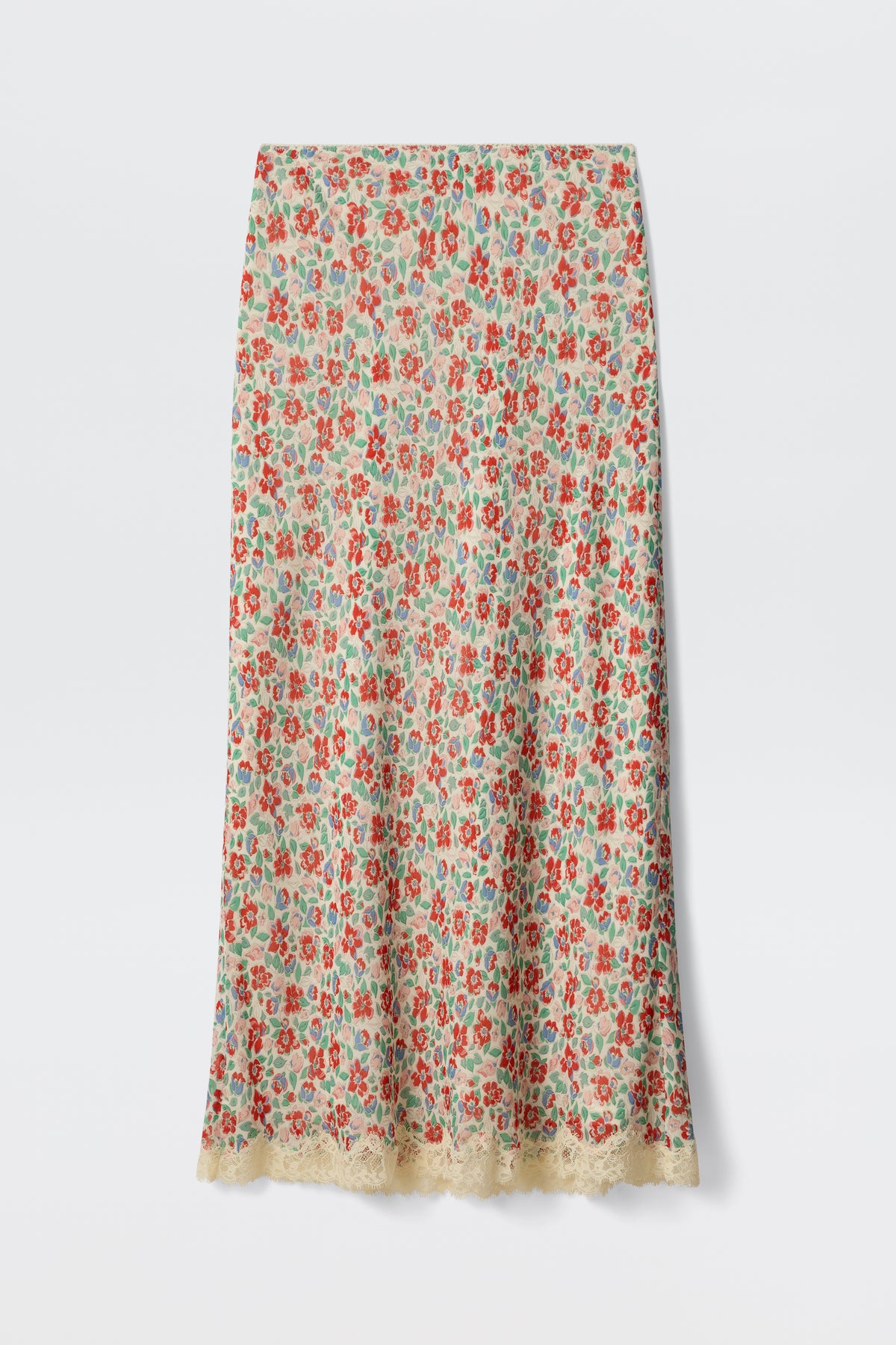 The Stassie - Jeannie Bloom Ivory is a long, straight skirt featuring a colorful red, green, and blue floral pattern on an ivory base with delicate beige lace trim along the hem.
