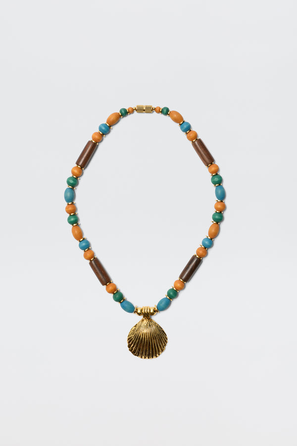 The Darielle - Multi necklace features alternating turquoise, brown wooden, and orange beads with a gold seashell pendant at the center, shown on a plain white background.
