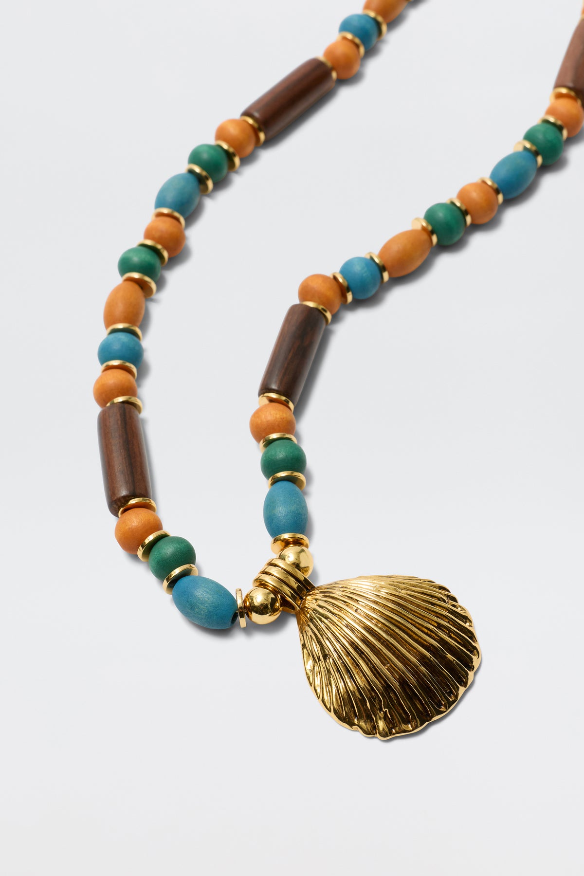 The Darielle - Multi necklace features blue, turquoise, brown, and gold round and cylindrical beads—some wooden—in a repeating pattern and is finished with a striking gold-plated shell pendant.