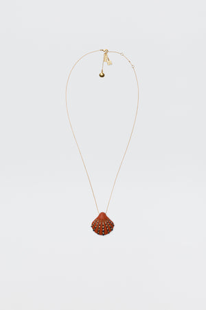 The Leanira - Orange necklace features a scallop shell-shaped pendant with small decorative studs on a gold-plated chain, shown against a plain white background.