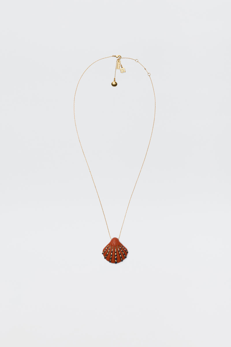 The Leanira - Orange necklace features a scallop shell-shaped pendant with small decorative studs on a gold-plated chain, shown against a plain white background.