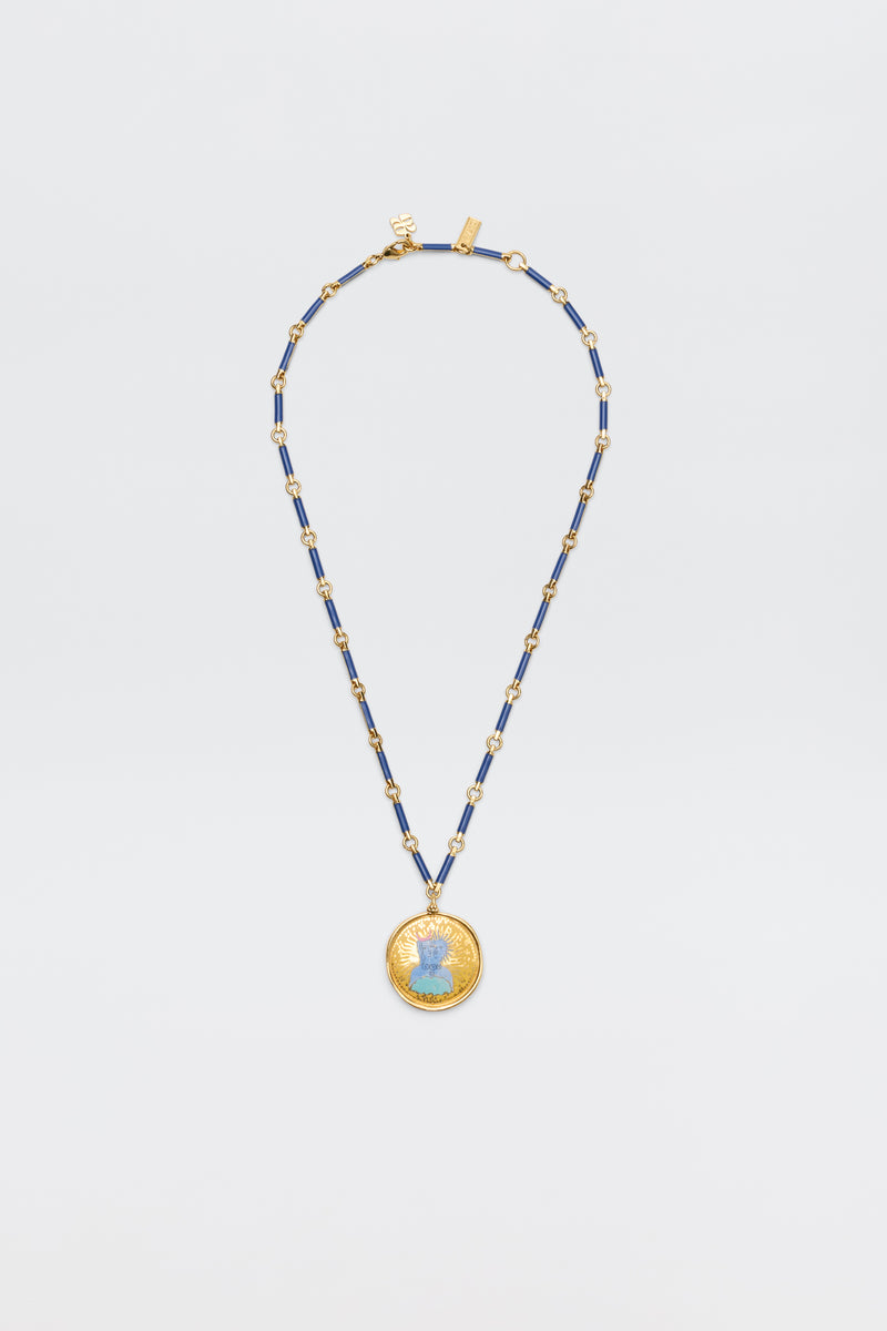 The Ari - Astro Gemini necklace features alternating blue and gold rectangular beads and a large round disc charm with a blue woman's profile at the center, shown against a plain white background.