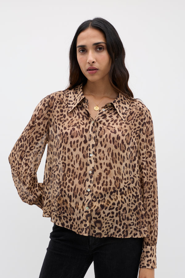 A woman with long dark hair wears the Blake - Mila Leopard Brown top and black pants, standing against a plain white background.