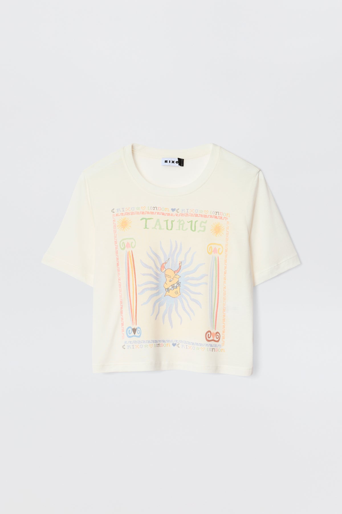 The Ria - Taurus is a cream short-sleeve tee with a vibrant Taurus illustration, astrological symbols, sun rays, and pastel decorative borders—ideal for pairing with RIXO skirts.