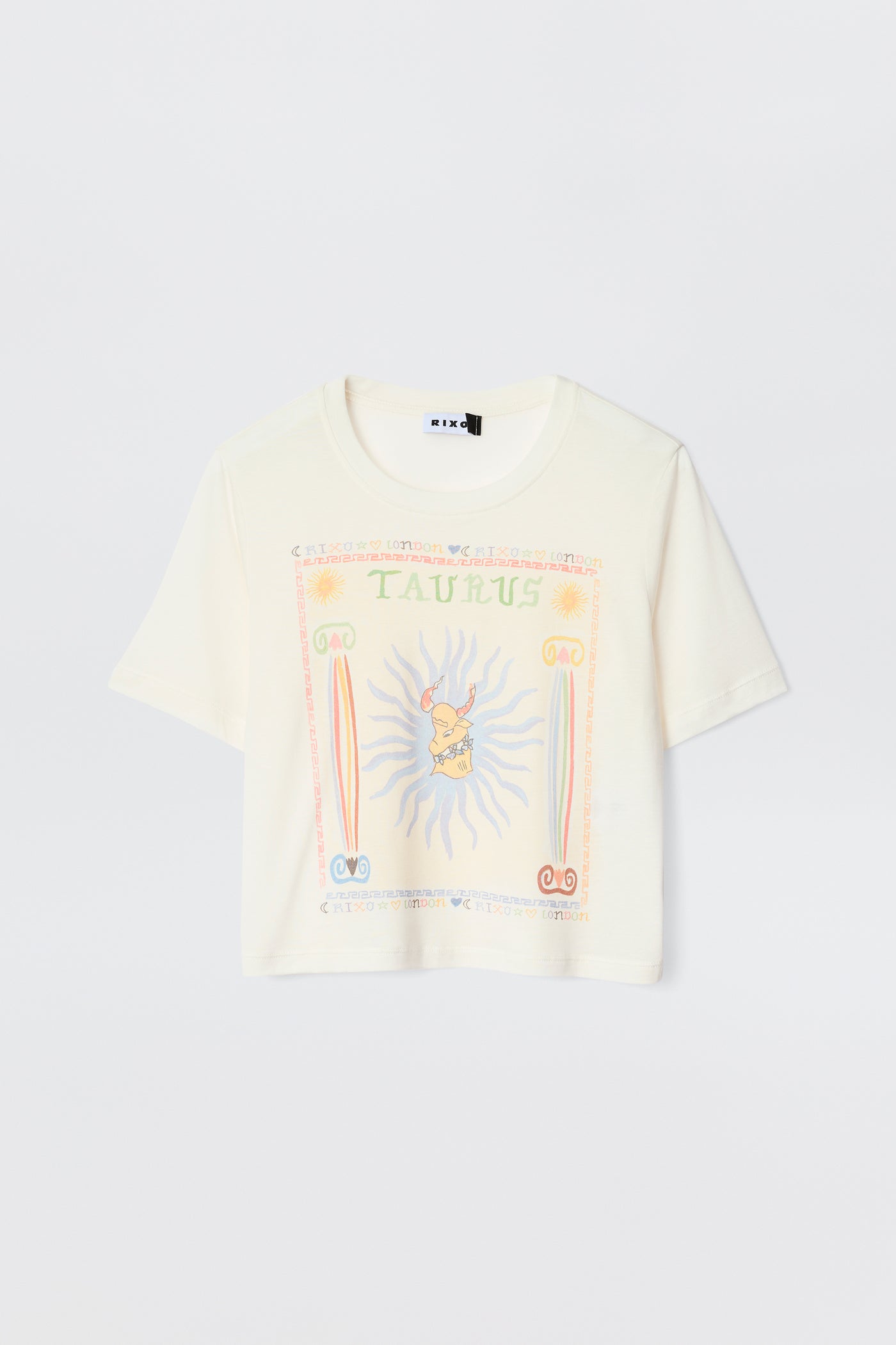 The Ria - Taurus is a cream short-sleeve tee with a vibrant Taurus illustration, astrological symbols, sun rays, and pastel decorative borders—ideal for pairing with RIXO skirts.