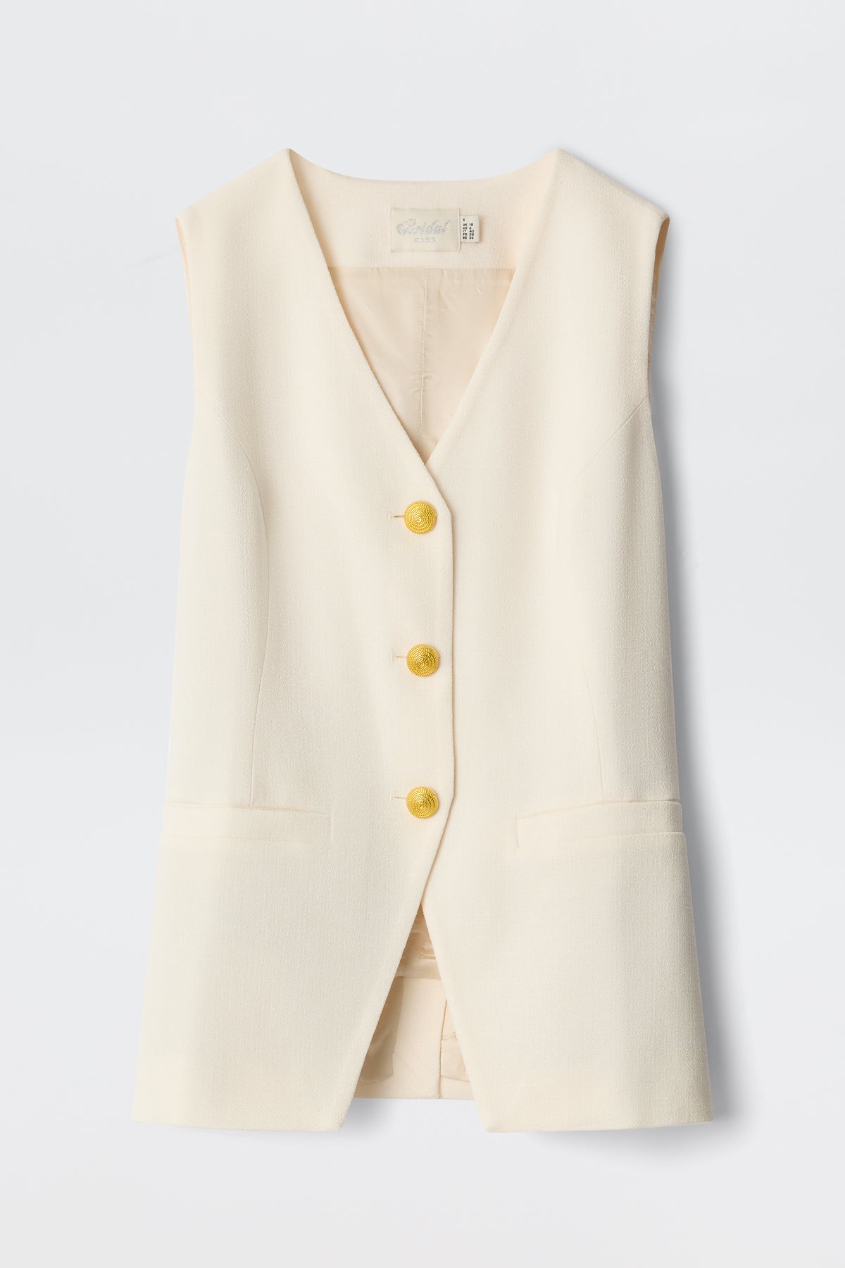 The Ingrida - Pearl is a sleeveless, cream-colored vest featuring a V-neckline, three gold buttons down the front, and two front pockets, displayed against a plain light background.