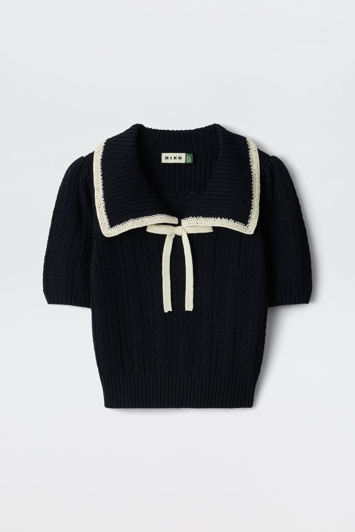 The Pippa - Deep Navy is a short-sleeved knit sweater featuring a wide white-trimmed sailor collar, cream front tie, ribbed texture, and a slightly cropped fit.