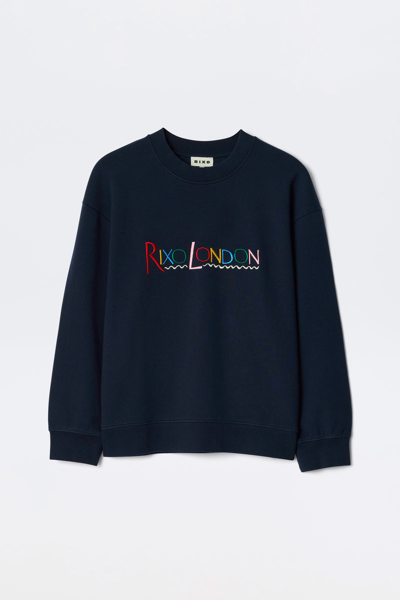 The Blaze - London Embroidery Navy is a navy blue crewneck sweatshirt featuring RIXO LONDON in colorful, wave-underlined embroidery across the chest.
