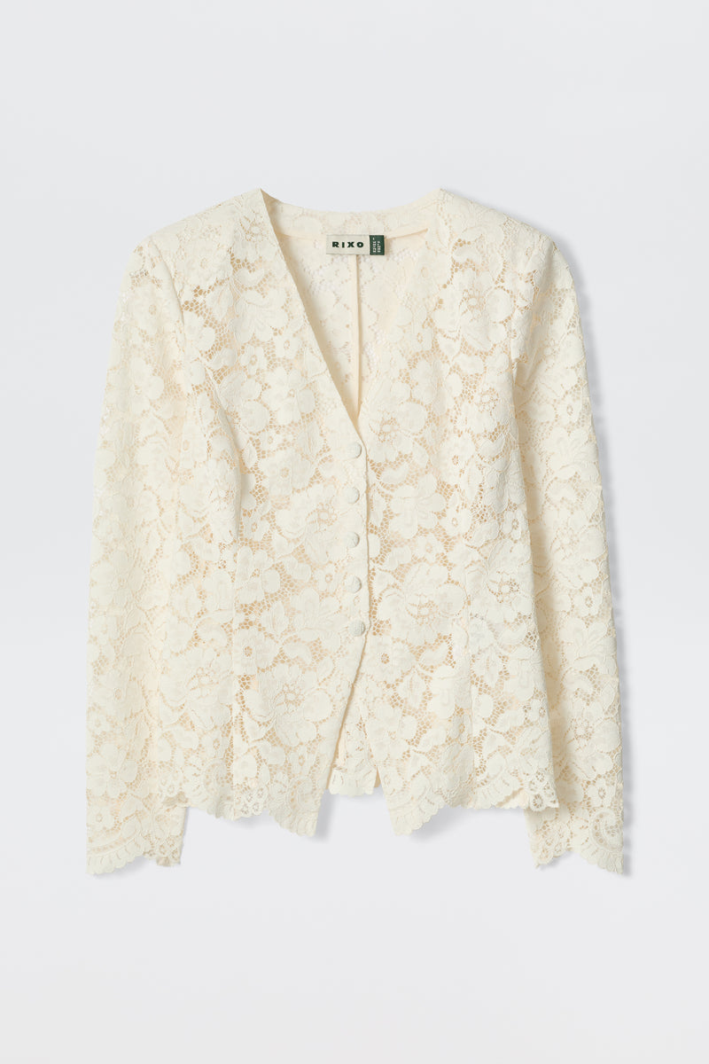 The Padma - Cream is an off-white, long-sleeved lace cardigan with a V-neckline and delicate floral pattern, shown flat on a light background.