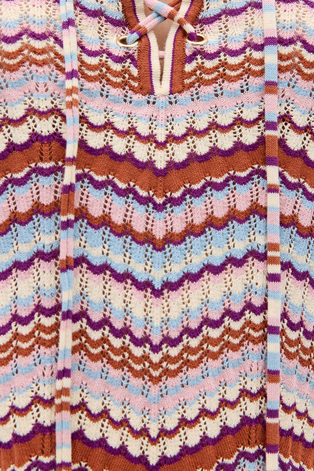 Close-up of the Brody - Maria Chevron Multi, a vintage-inspired women’s top crafted from retro cotton knit fabric with wavy chevron stripes in purple, brown, blue, white, and pink. Two striped drawstrings hang vertically, accentuating the lace-up detail at the top center for a charming finish.