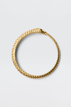 The Viera - Gold is a gold-plated snake bangle in a circular shape, designed as a serpent eating its tail with detailed scales and an antique finish. Displayed on a plain light gray background, it represents the ouroboros.