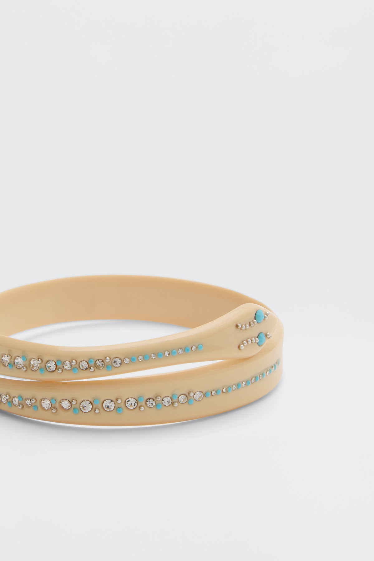 The Shereen - Cream features two beige bangle bracelets adorned with turquoise and clear rhinestones, displayed stacked against a plain white background.