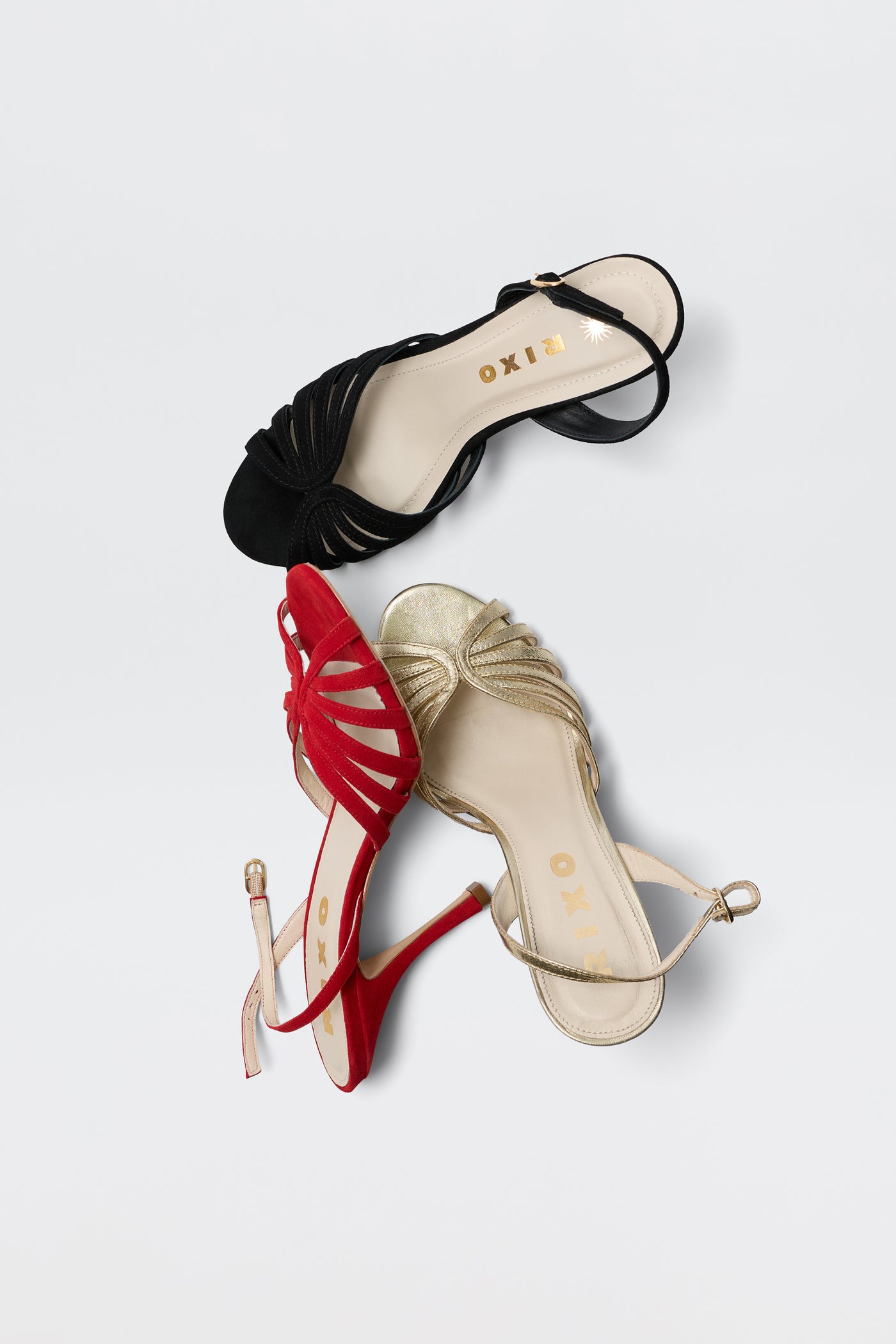 The Mavi - Red sandal from RIXO is a glamorous women's shoe with an open toe, ankle strap, and front knot detail, shown here alongside black and gold variants on a white background. The RIXO logo appears inside each sandal.
