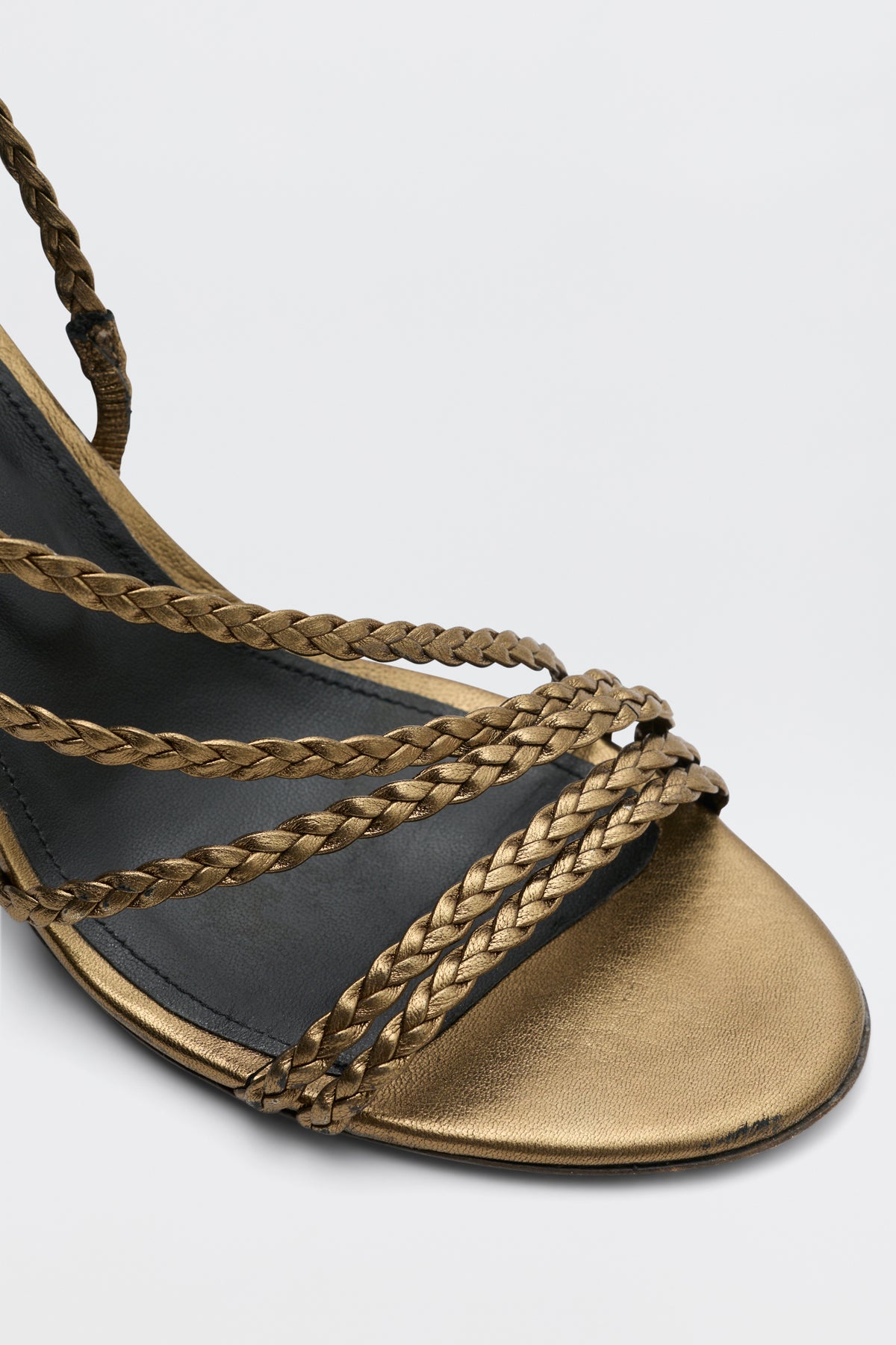Close-up of the Gracey - Gold sandal, featuring several braided gold metallic straps over the toes and a partially visible footbed, set against a plain white background.