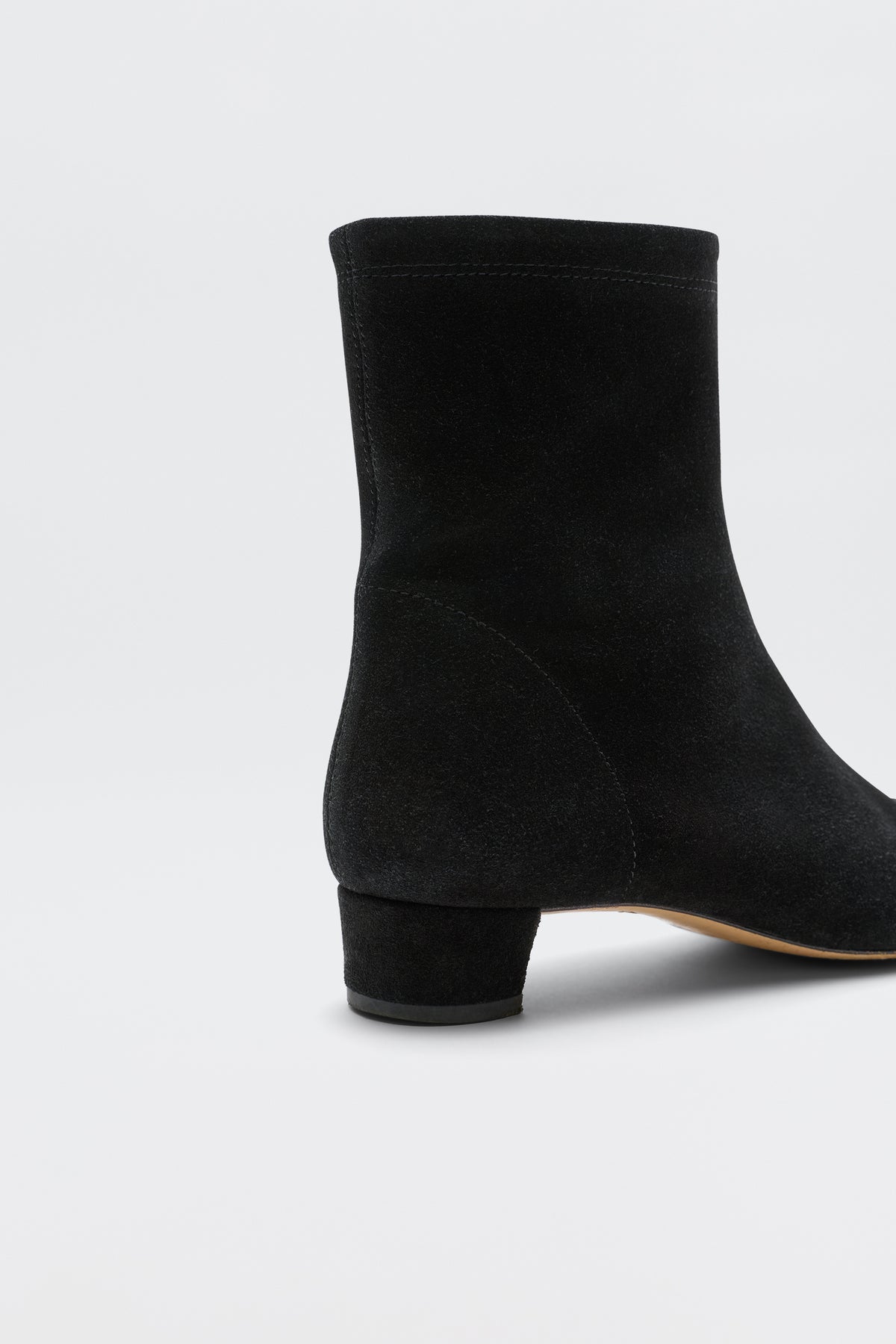 A close-up of Rey - Black, a black suede ankle boot with a low, feminine heel, photographed against a plain white background.