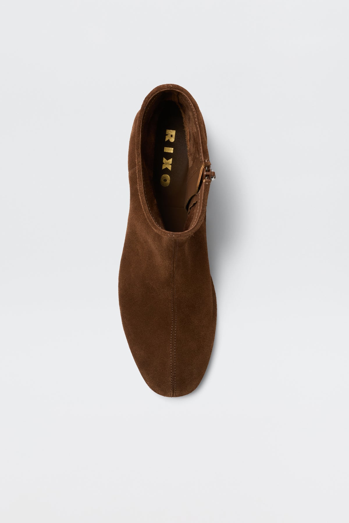 Top view of the Rey - Chocolate ankle boot in brown suede with a side zipper, shown on a white background. The gold RIKO brand name is visible inside the shoe.