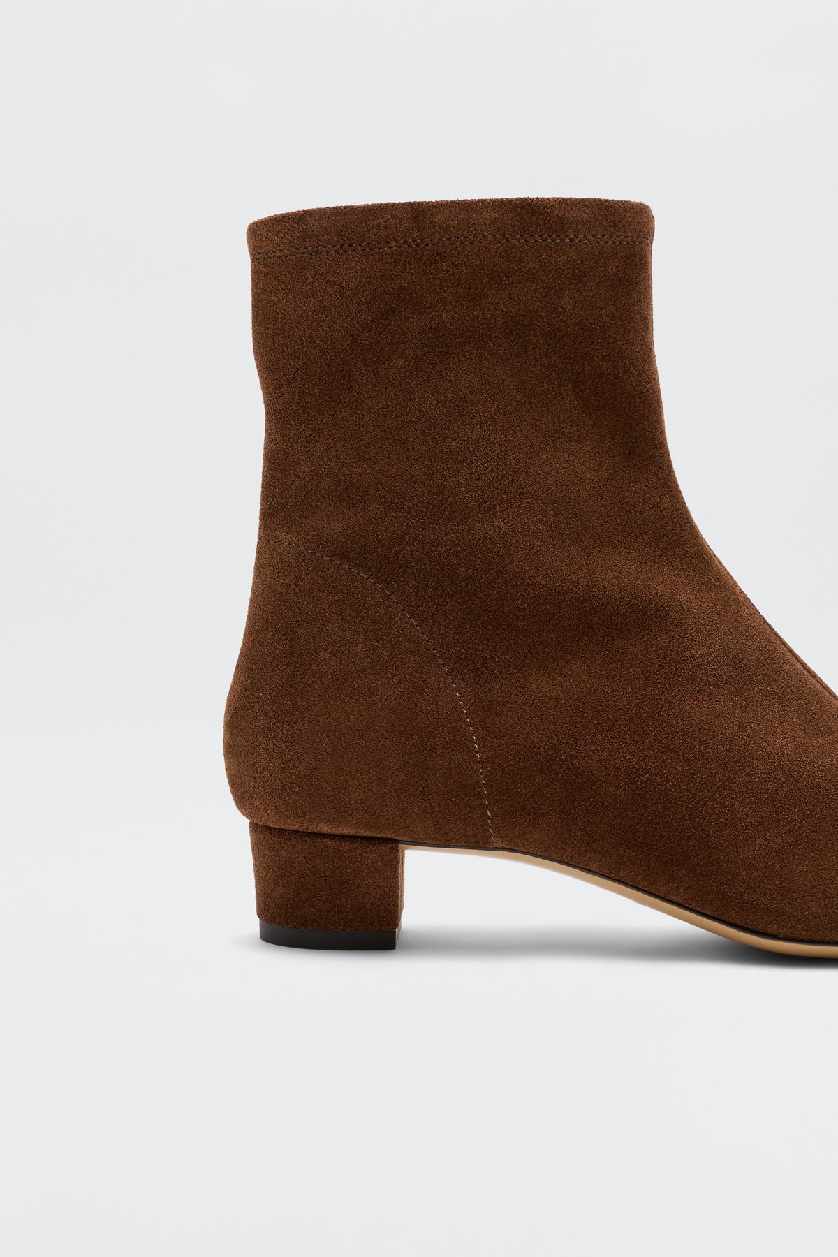 A close-up of the Rey - Chocolate ankle boots in brown suede, showcasing a low chunky heel, set against a plain white background.