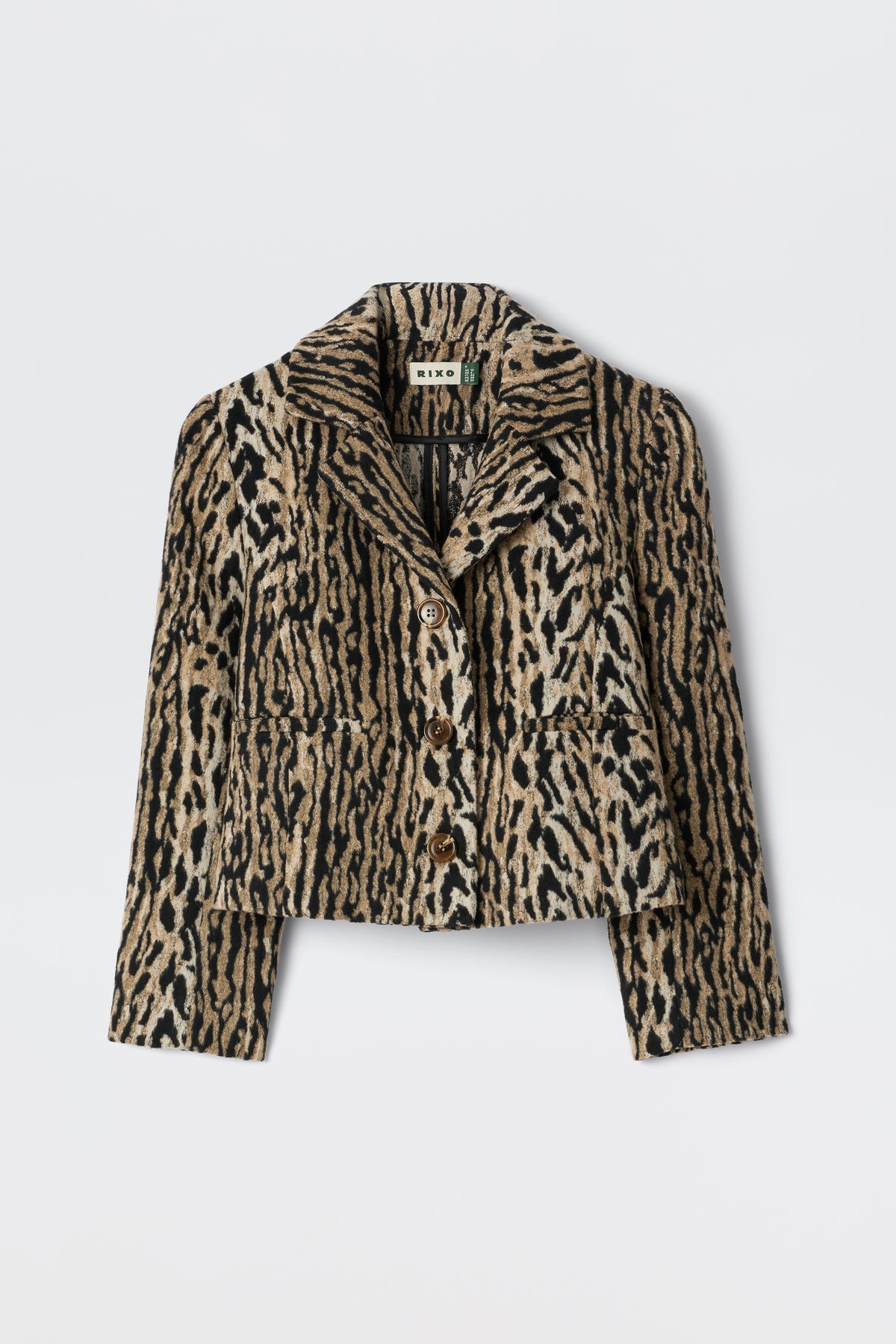 The Leila - Bohemia Leopard Brown is an elegant cropped button-up jacket with a bold beige, brown, and black leopard print, collar, and front pockets. Inspired by vintage souvenir jackets, it's shown on a plain white background.