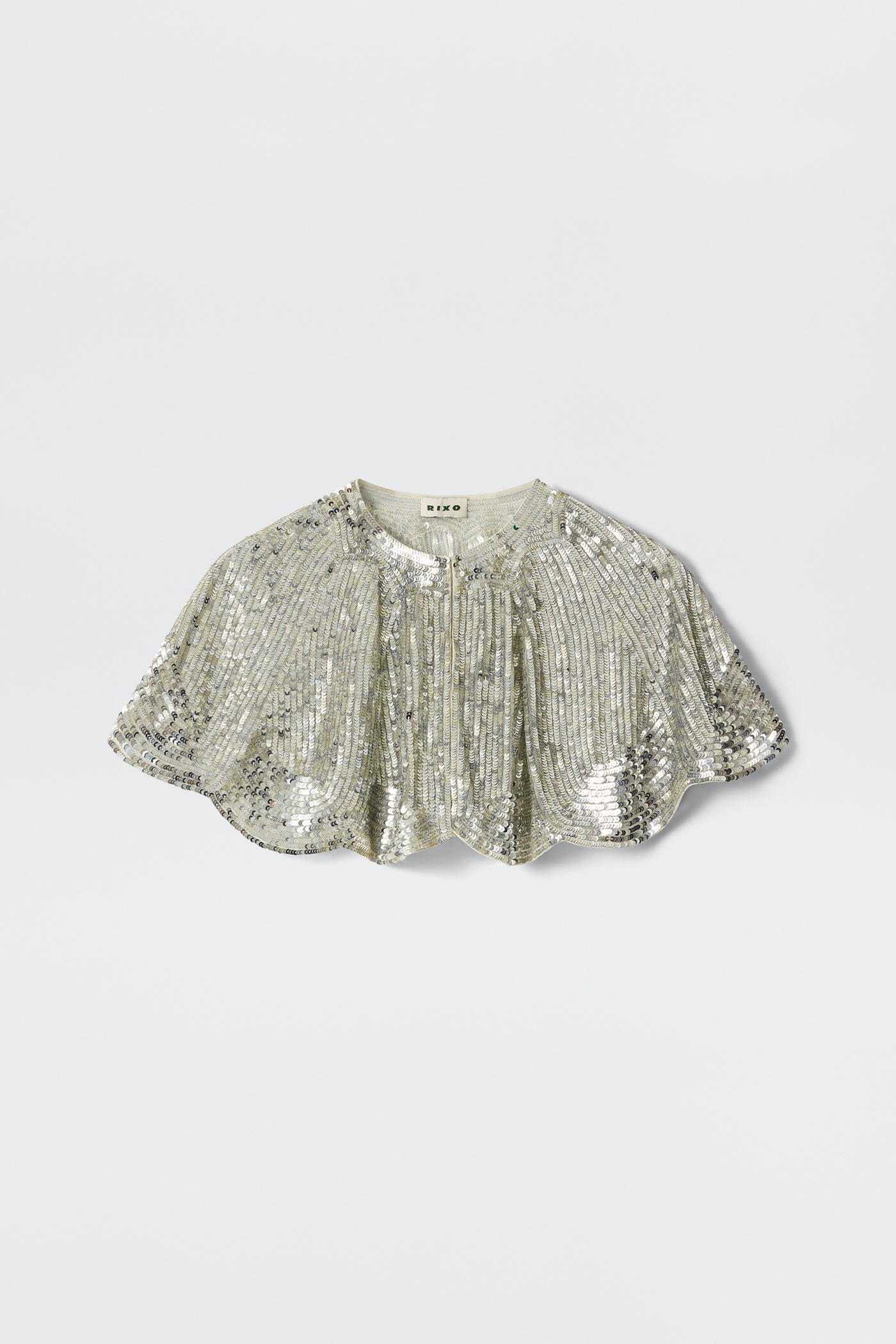 The Evienne - Art Deco Embellishment Pearl is a silver sequin capelet featuring a short, scalloped hem and gathered details, inspired by Art Deco capes, shown against a plain light background.