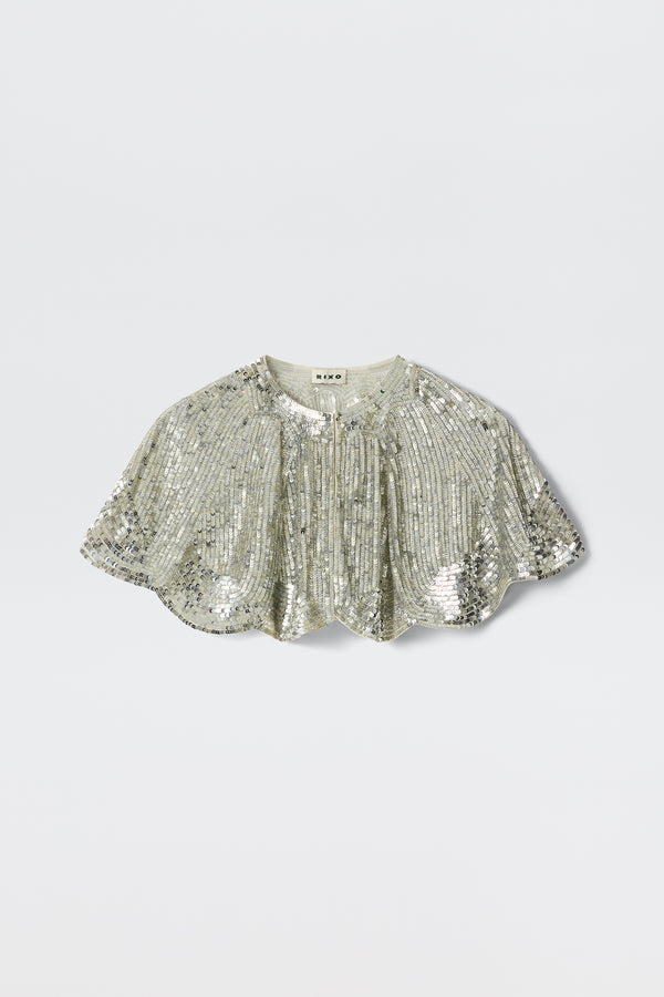 The Evienne - Art Deco Embellishment Pearl is a silver sequin capelet featuring a short, scalloped hem and gathered details, inspired by Art Deco capes, shown against a plain light background.