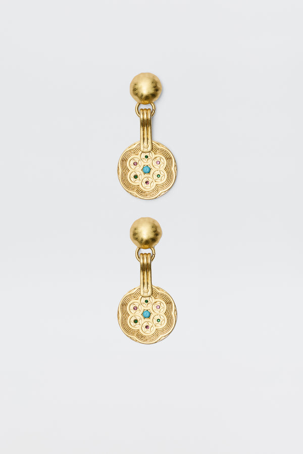 A pair of Anouk - Gold drop earrings with round, textured discs featuring a circular pattern and central colored gemstones, attached to smooth gold studs. Vintage-inspired, photographed on a plain white background.