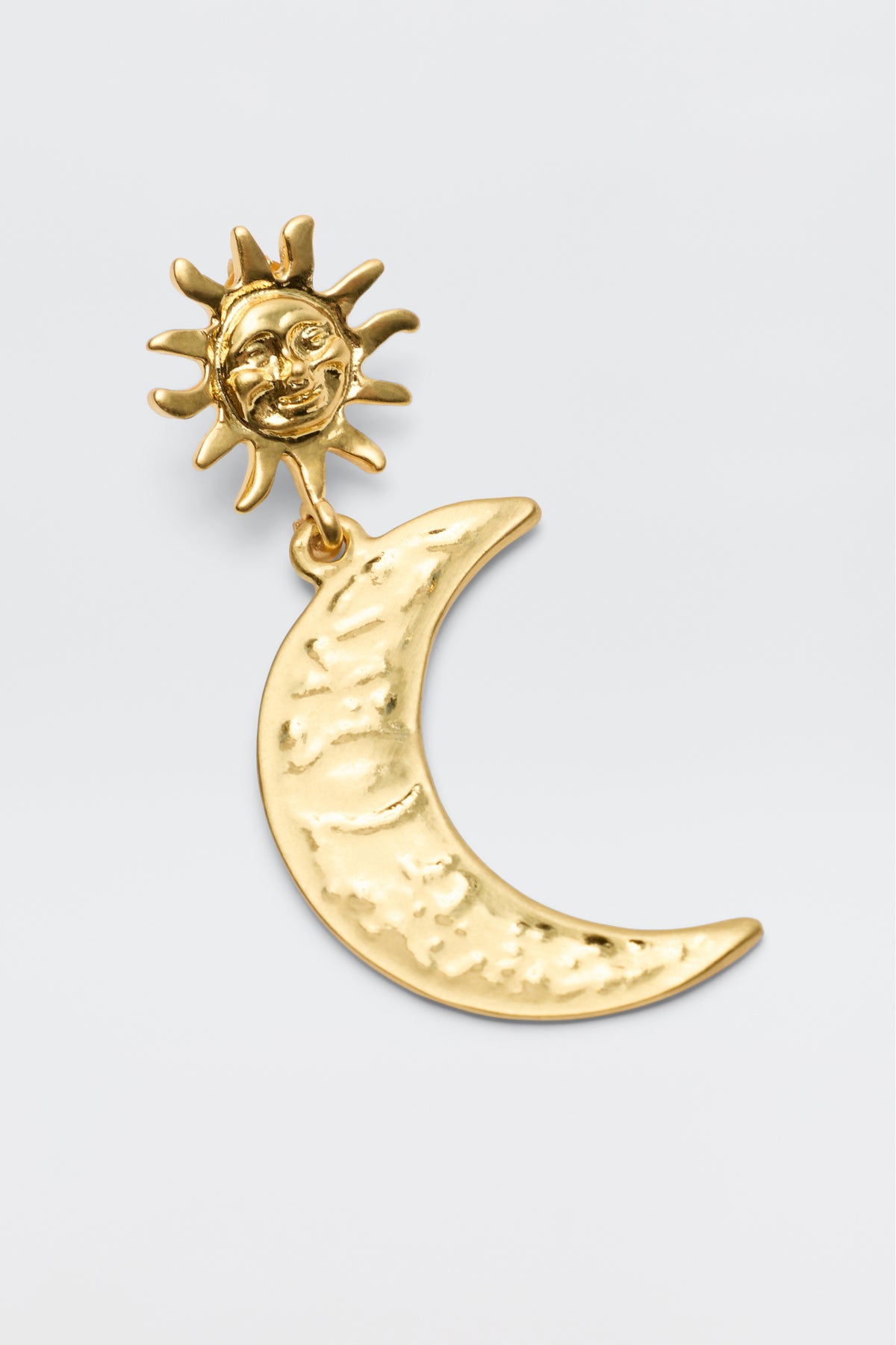 Meet Davies - Gold: a gold-plated celestial earring showcasing a sun with a face atop a textured crescent moon. Set against a plain background, it's perfect for vintage style earring lovers.