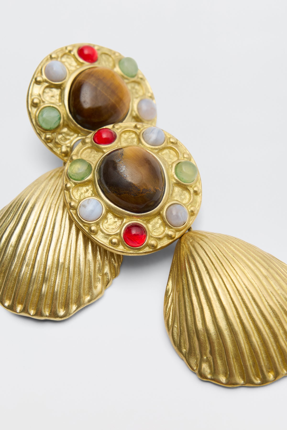 Vixon - Gold: Ornate gold earrings with shell-shaped bottoms, textured round tops featuring large brown stones, and circular patterns of red, green, and white stones.