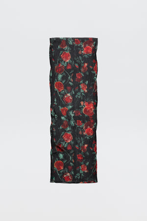 The Julien - Claudia Rose Black is a long, rectangular black scarf featuring red rose patterns with green leaves, displayed against a plain light background.